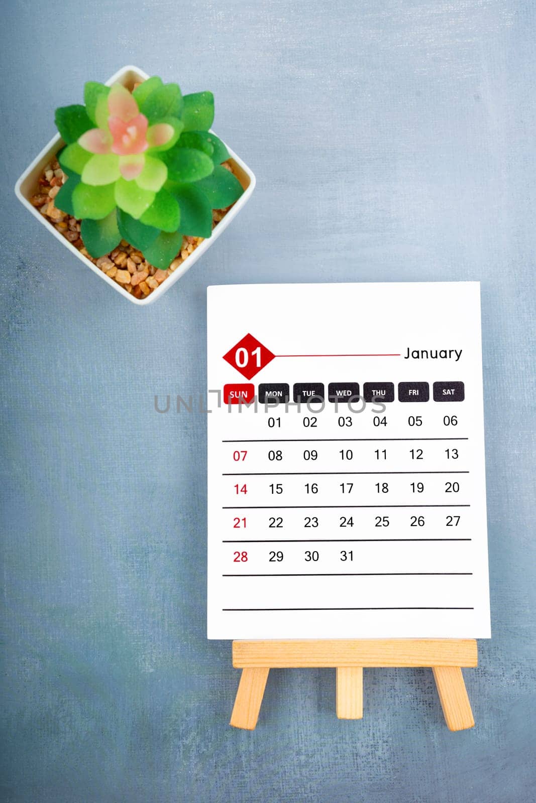 2024 January calendar page and plant pot on blue wooden background.