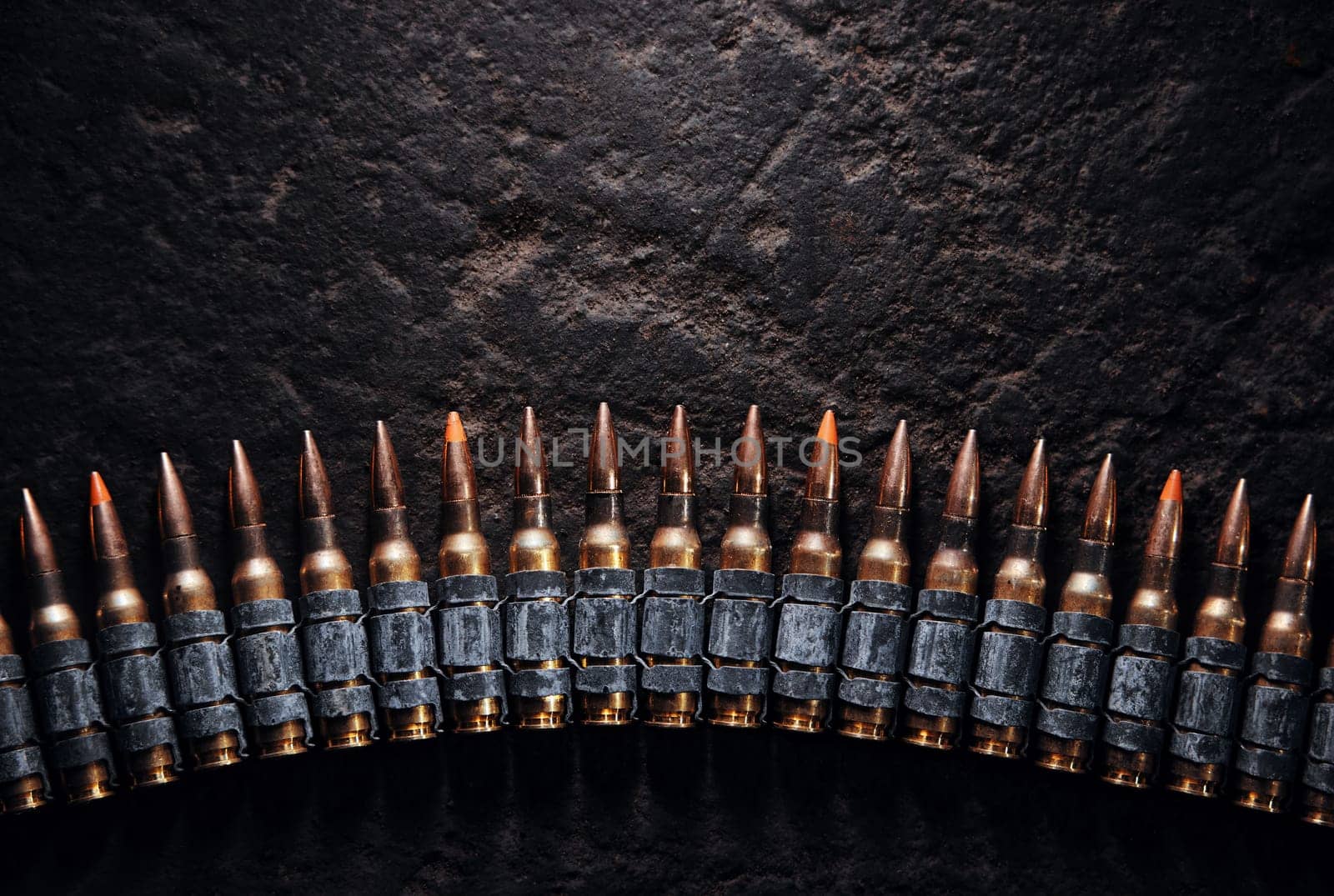 Machine gun bullet belt on the floor. Background on the military theme. Ammo, chain of ammo on concrete background. Top view of machine gun belt cartridge 7.62 mm caliber on dark background by EvgeniyQW