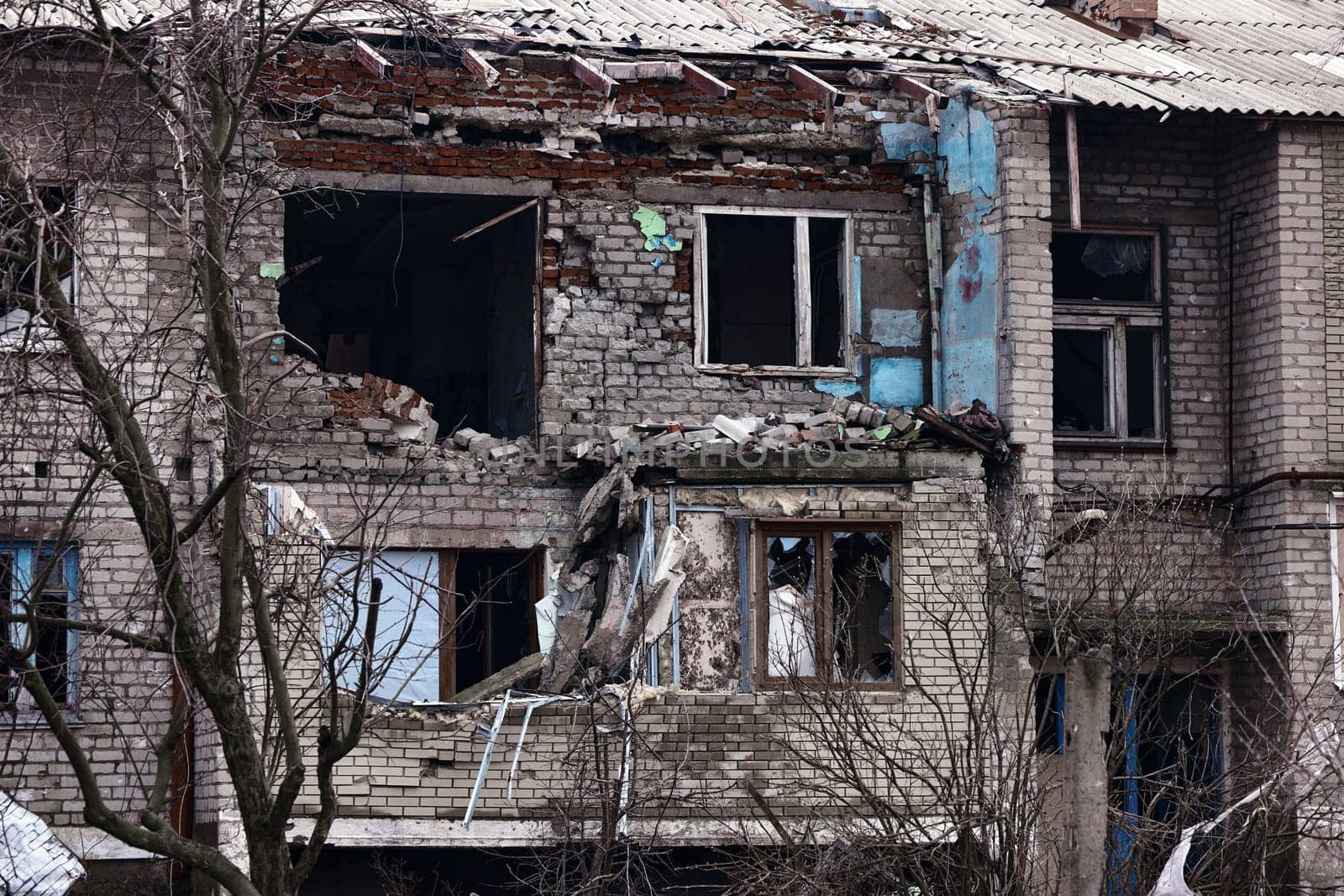 An apartment building in a war zone. Damage to a house as a result of artillery strikes. War in residential areas, broken windows and burned apartments. Armed Conflict in Ukraine by EvgeniyQW