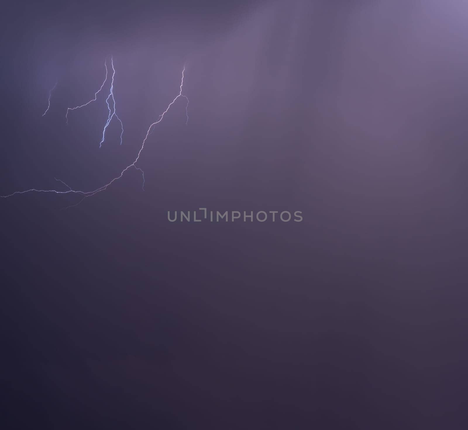 Dramatic lightning illuminates a purple night sky, showing nature's might.