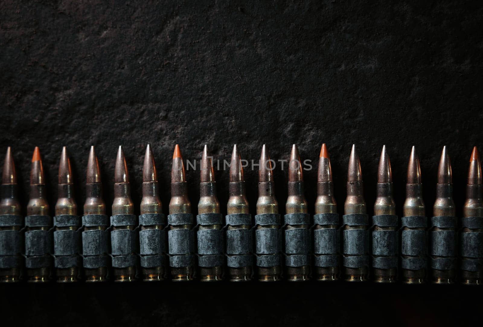 Machine gun bullet belt on the floor. Background on the military theme. Ammo, chain of ammo on concrete background. Top view of machine gun belt cartridge 7.62 mm caliber on dark background by EvgeniyQW