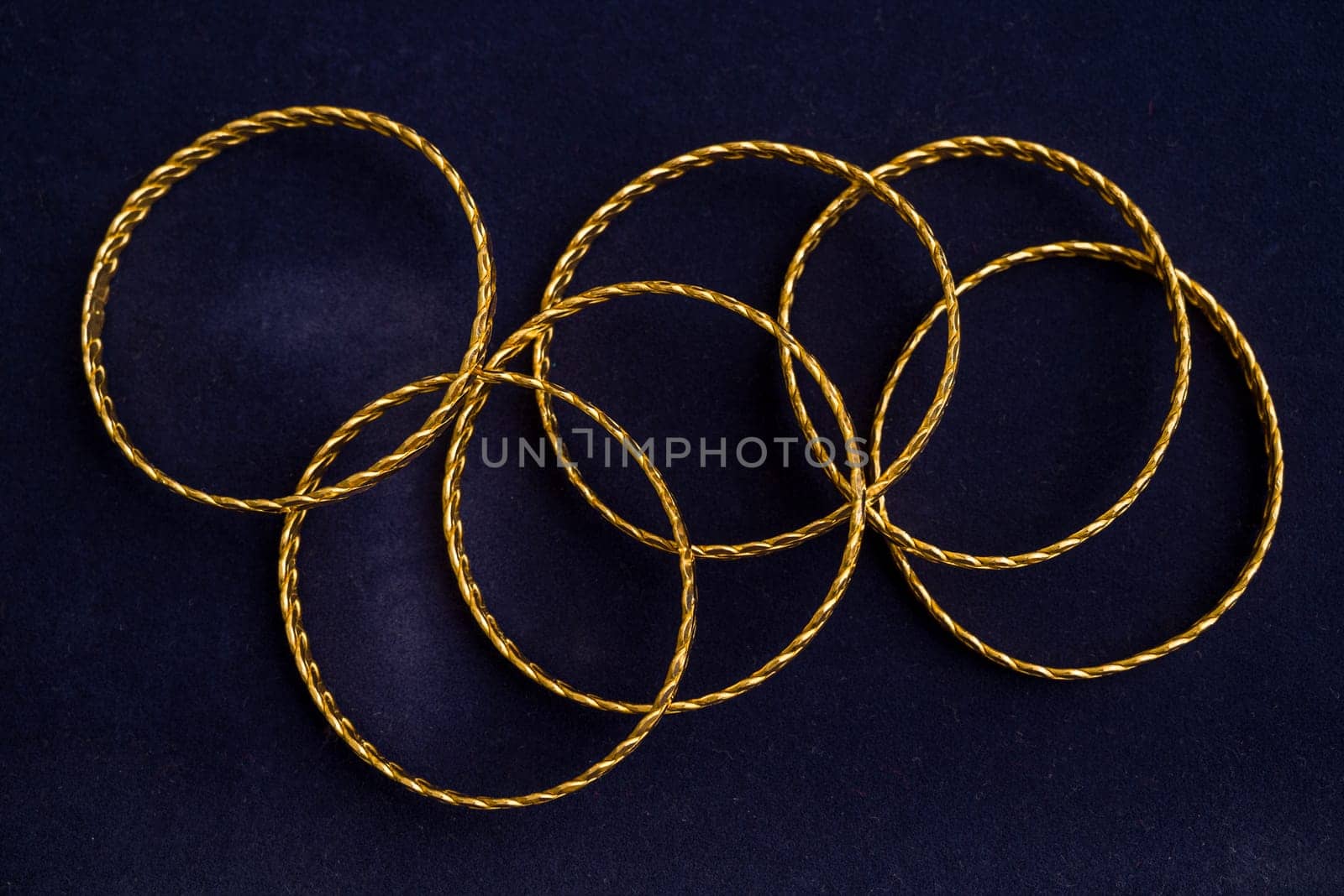 24k (24 carat) Turkish gold twist bracelet standing in a heap on a dark blue background in the gold store