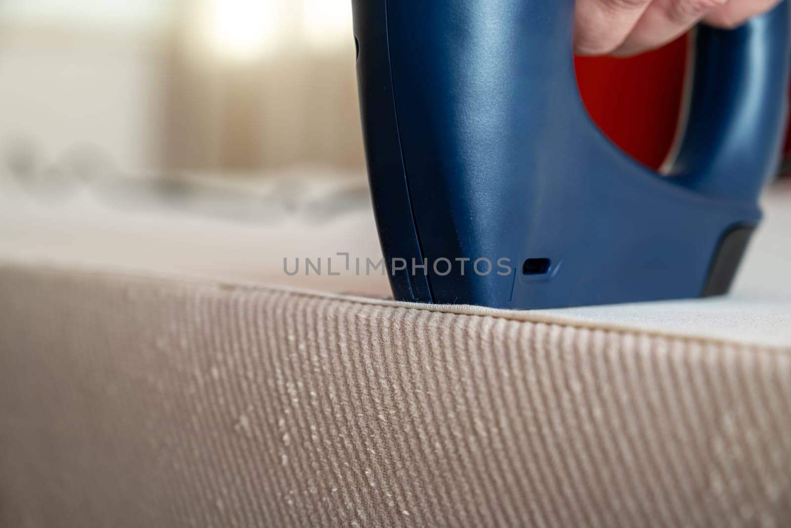 Worker stapling sofa lining with electric staple gun