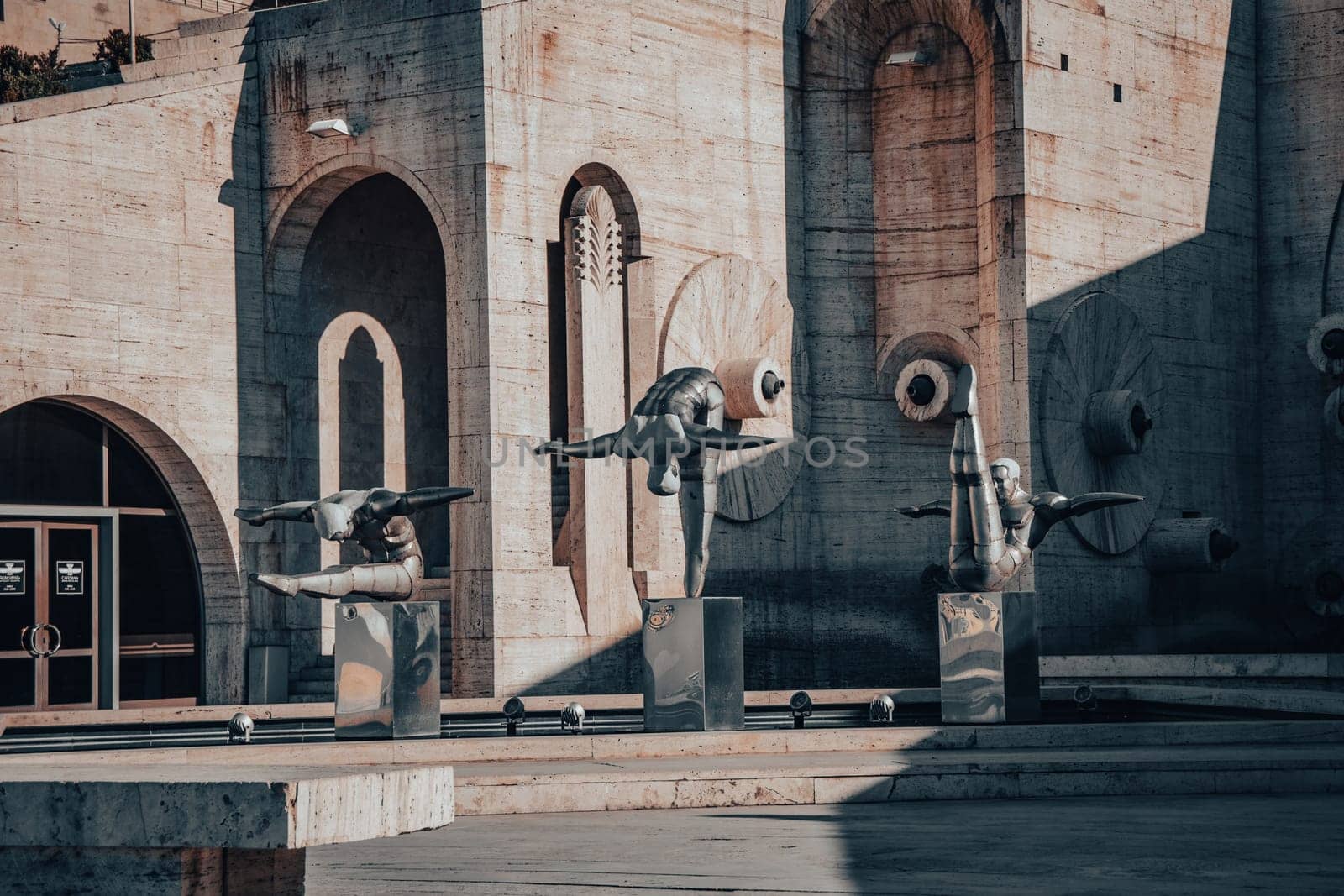 Modern art - stainless steel sculptures of three athletes in the pool concept photo. Statues on top of Cascades in front of entrance door to a museum in Yerevan. High quality picture for magazine, article