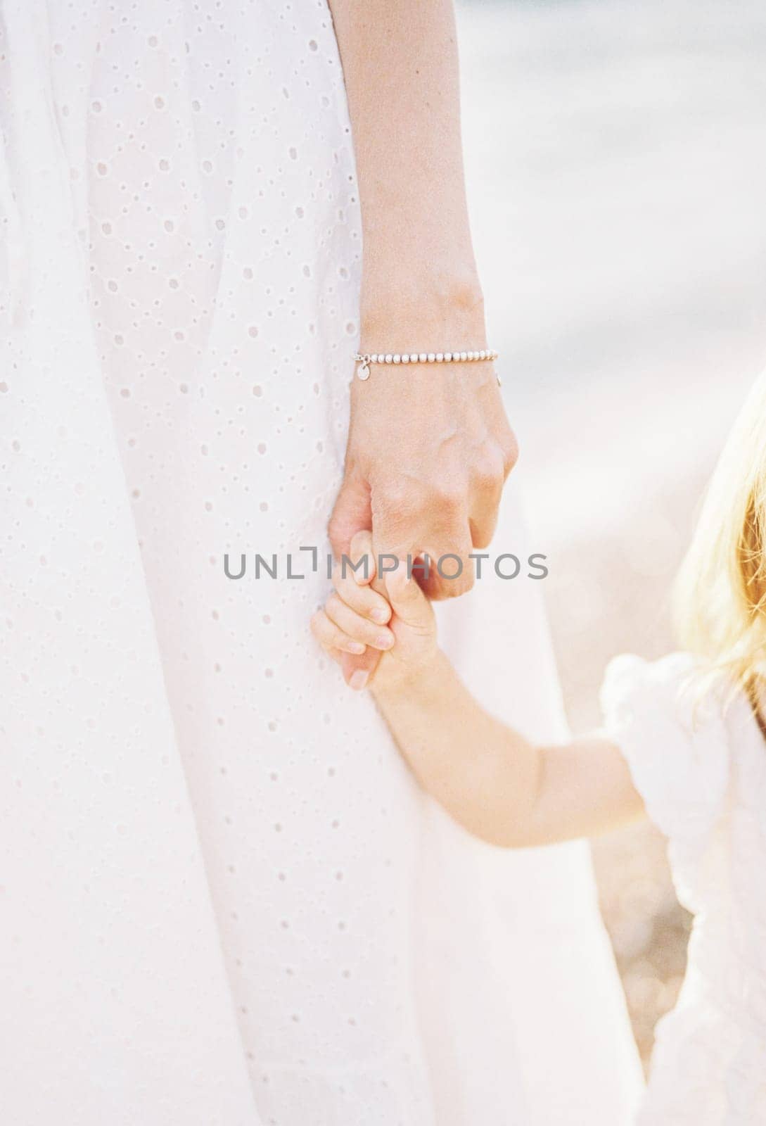 Little flower girl holds bride finger. Cropped. Faceless by Nadtochiy