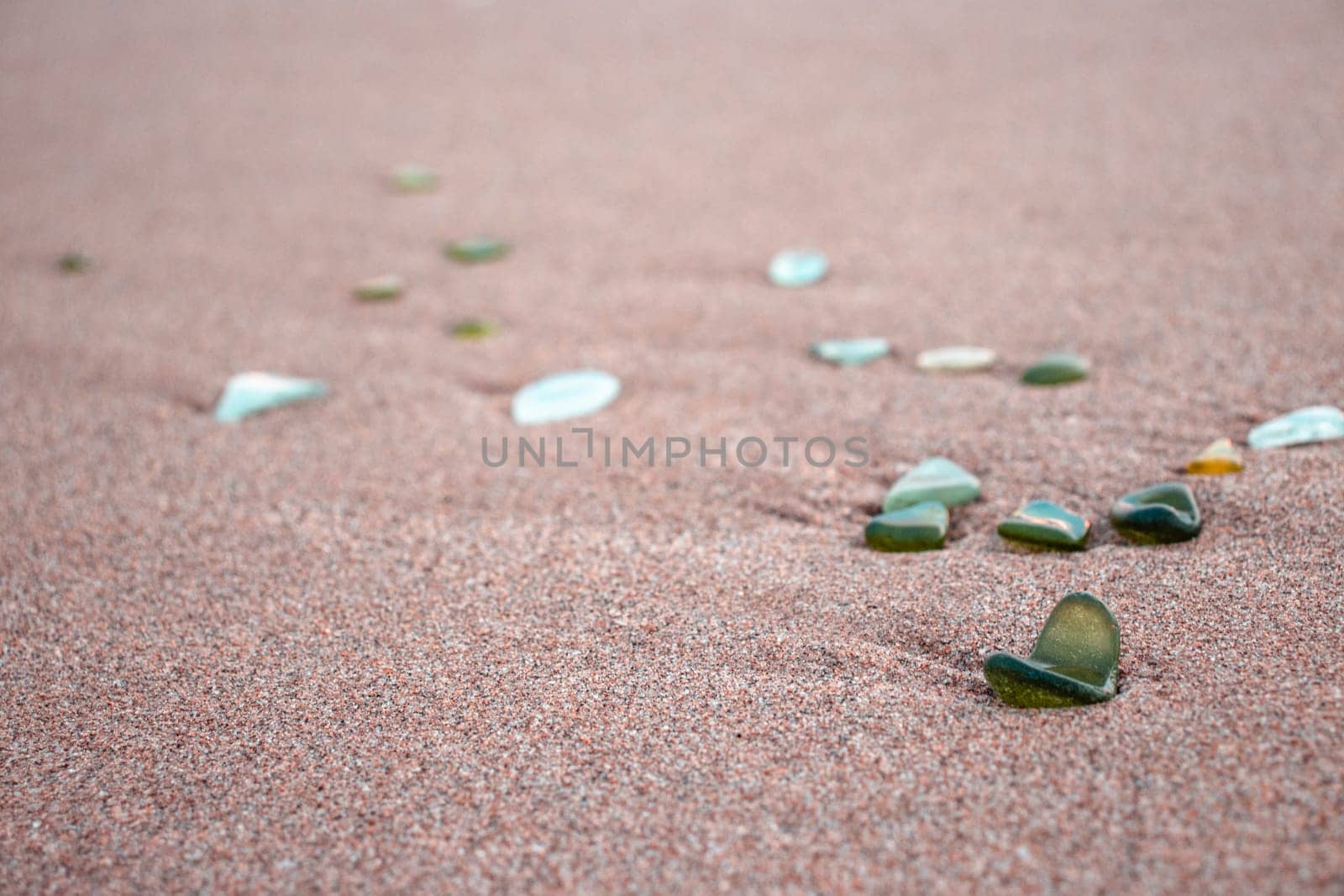 Sand beach and stones with foam concept photo. Glass stones from broken bottles polished by the sea. Front view photography with blurred background. High quality picture for wallpaper, travel blog