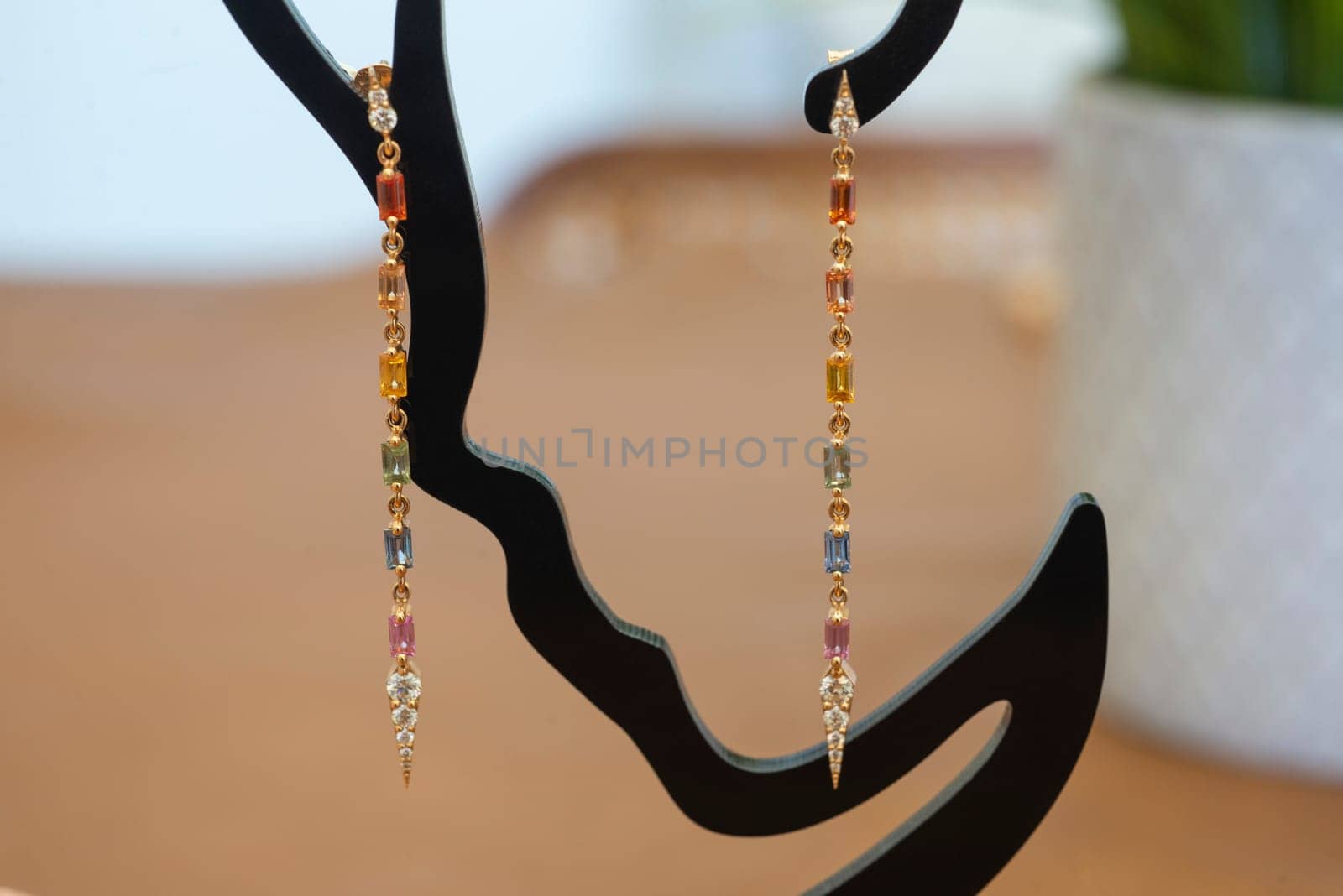 Pair of luxury expensive ladies dangling earrings jewelry hanging on display stand with a selection variety of precious gemstones