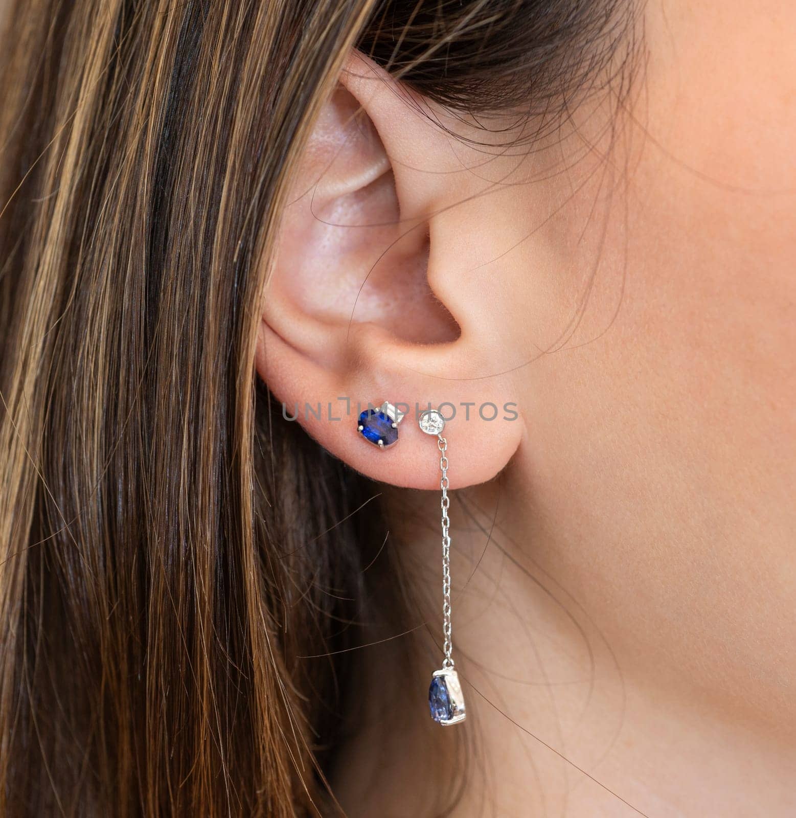 Closeup detail of ladies female ear with luxury expensive earrings and precious gemstones