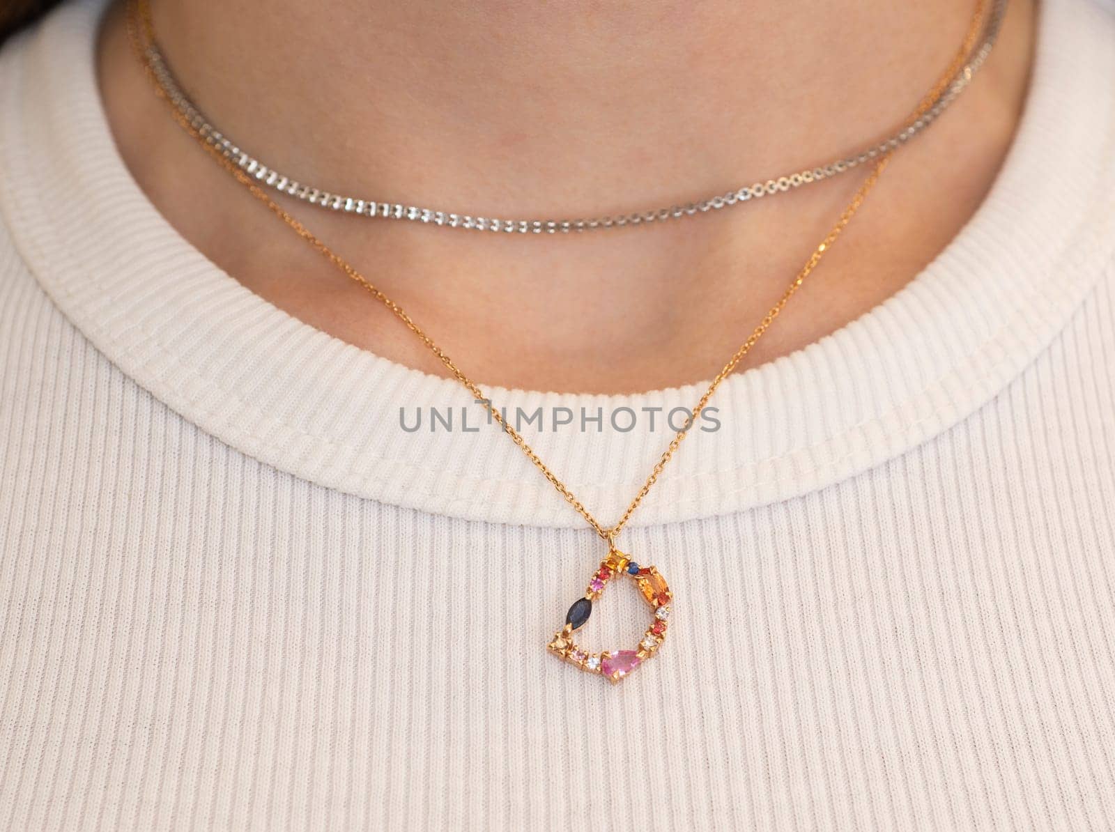 Closeup detail of woman wearing ladies expensive luxury gold necklace jewelry with precious gemstones