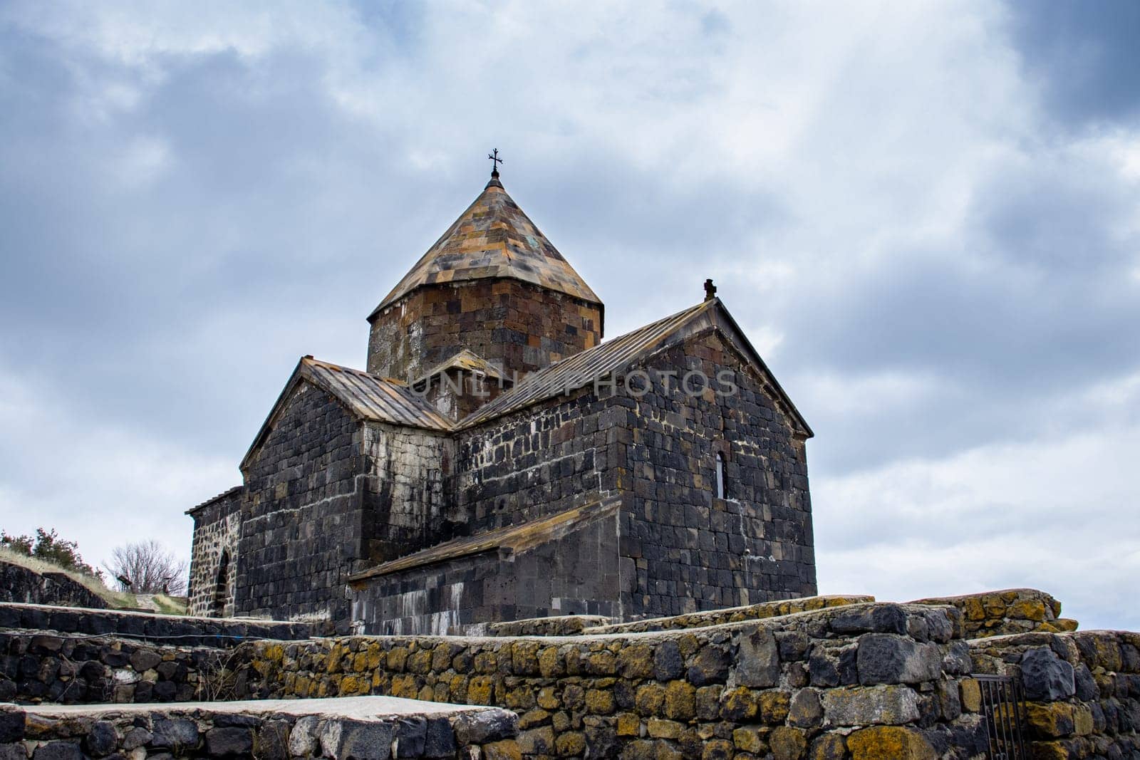 Monastery located on the shore of Lake Sevan concept photo. Monastery complex under dramatic spring sky. High quality picture for wallpaper