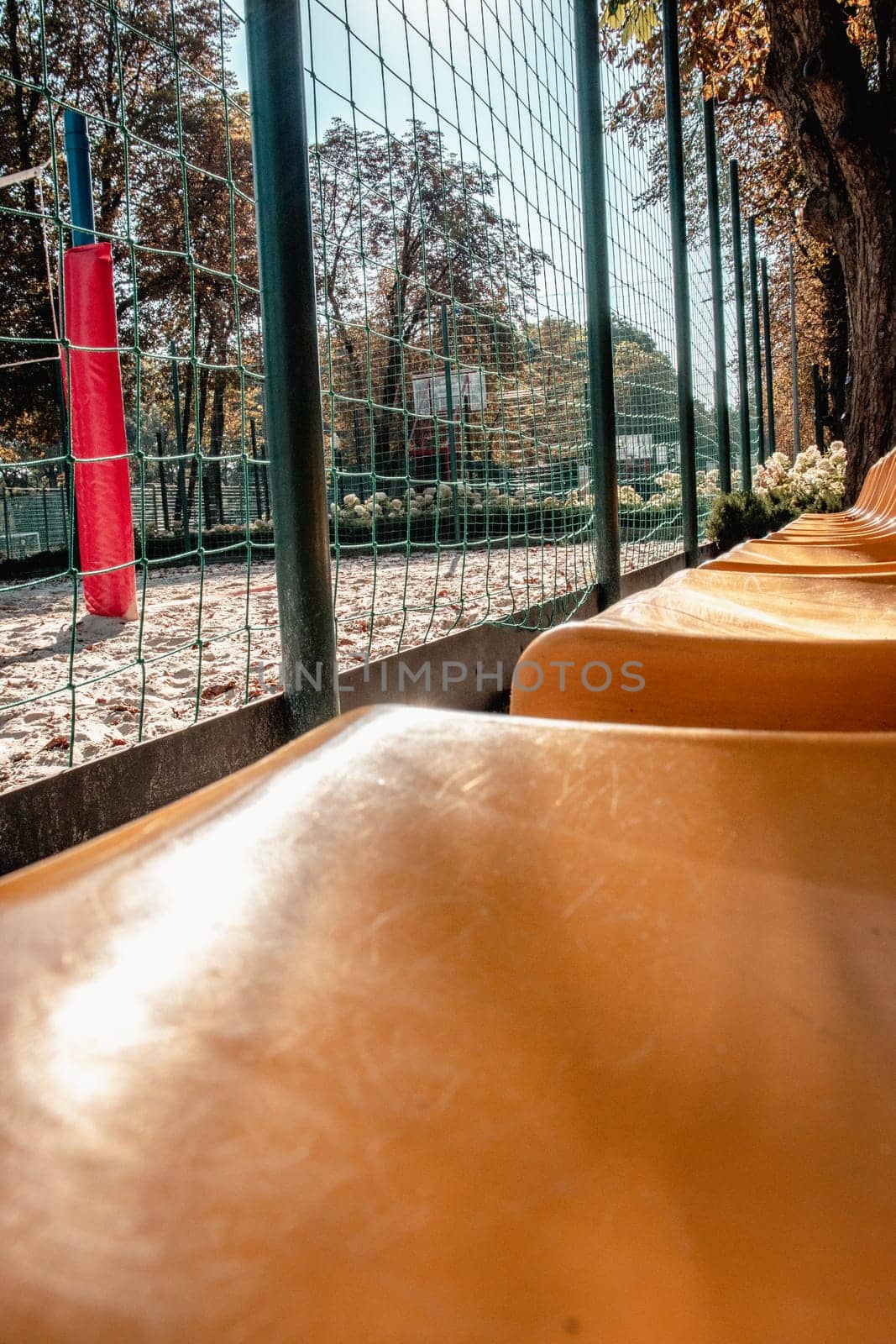 Close up yellow seats of tribune in near playground concept photo. Chairs for audience in park. Cultural environment concept. Empty seats, modern stadium. High quality picture for wallpaper