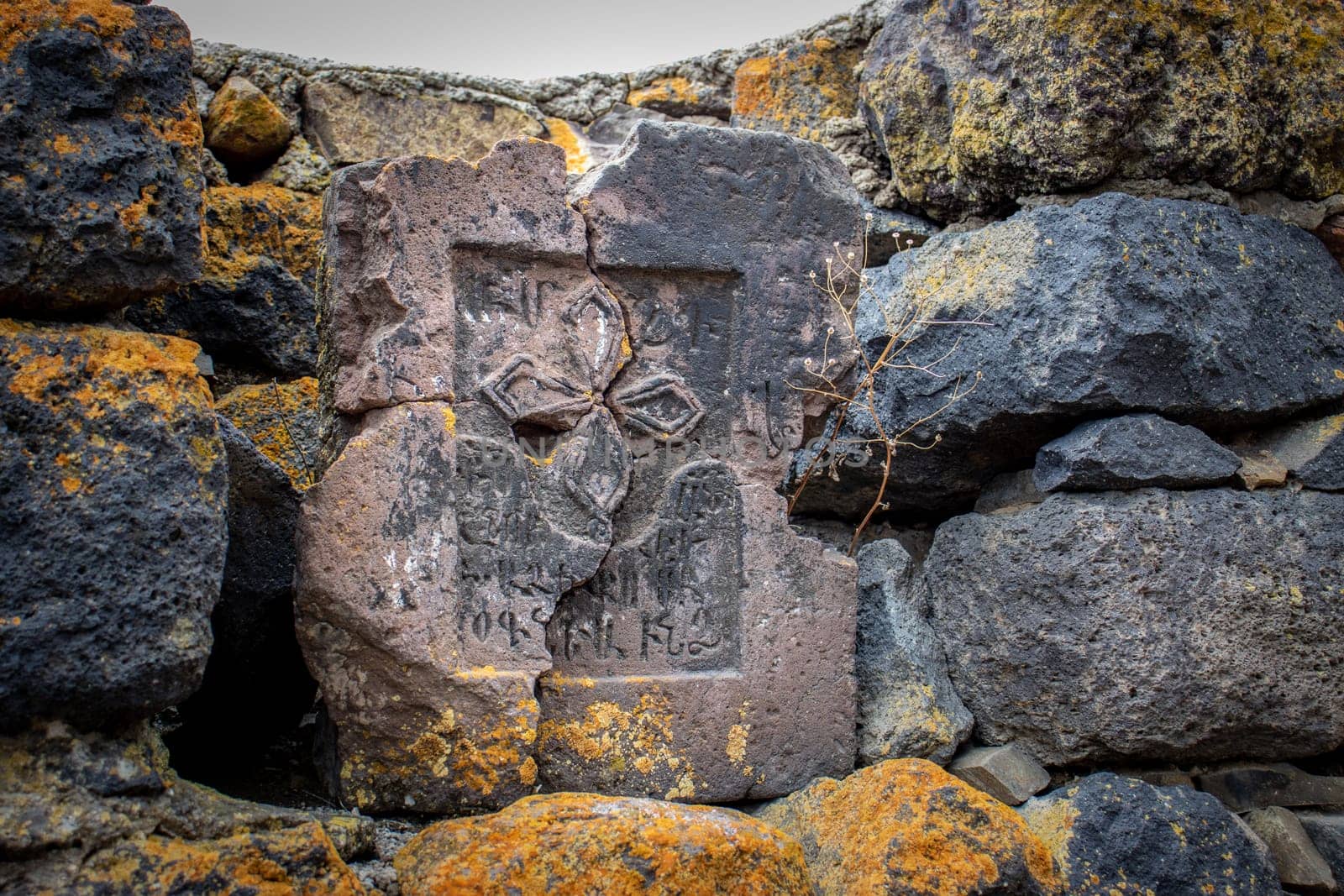 Close up stone cross on rough stone wall concept photo. Historical tombs and head stones. Rocks full of the moss texture in nature for wallpaper.