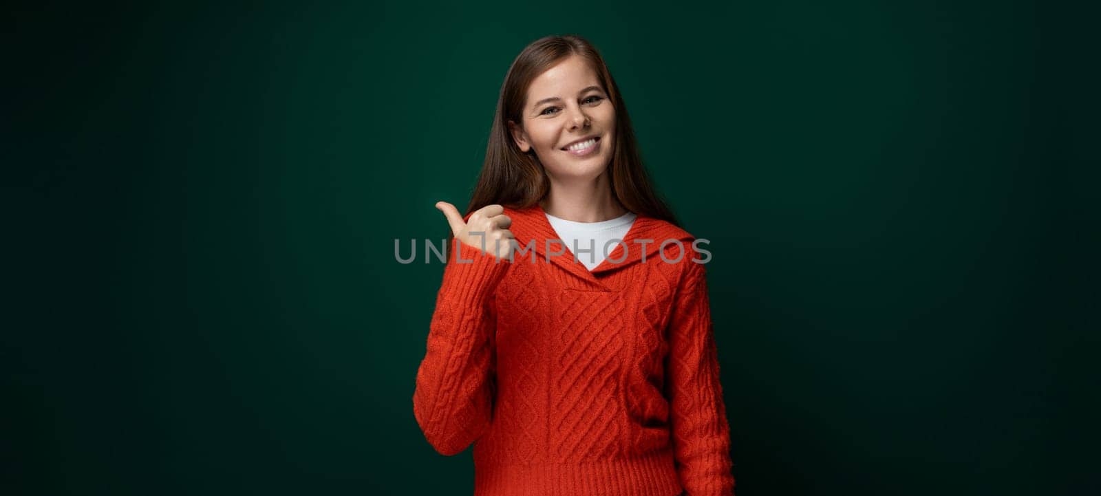 Successful Caucasian woman with brown hair wearing a red sweater on a green background by TRMK