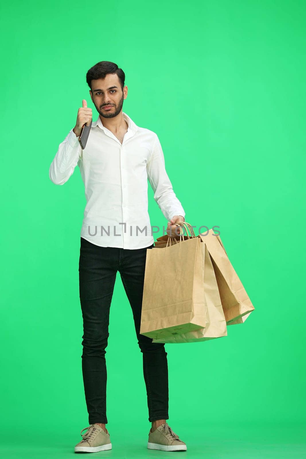Man on a green background with shoppers show thumb up.