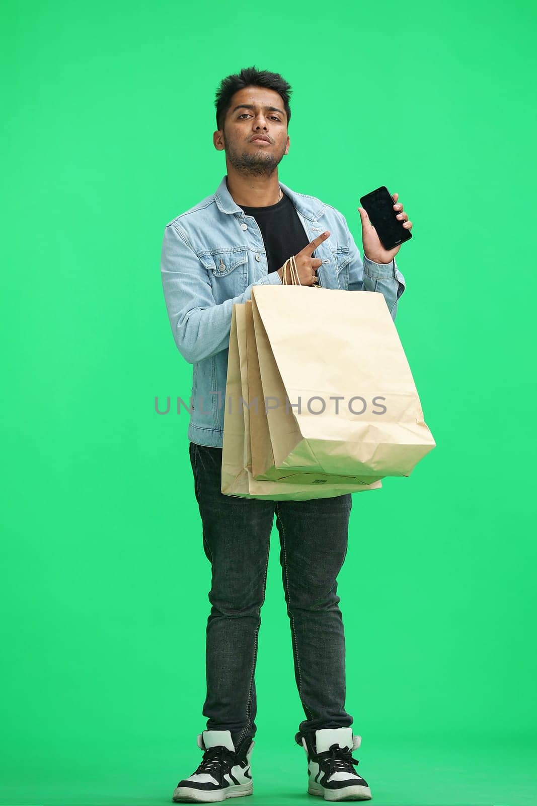 Man on a green background with shoppers show phone by Prosto