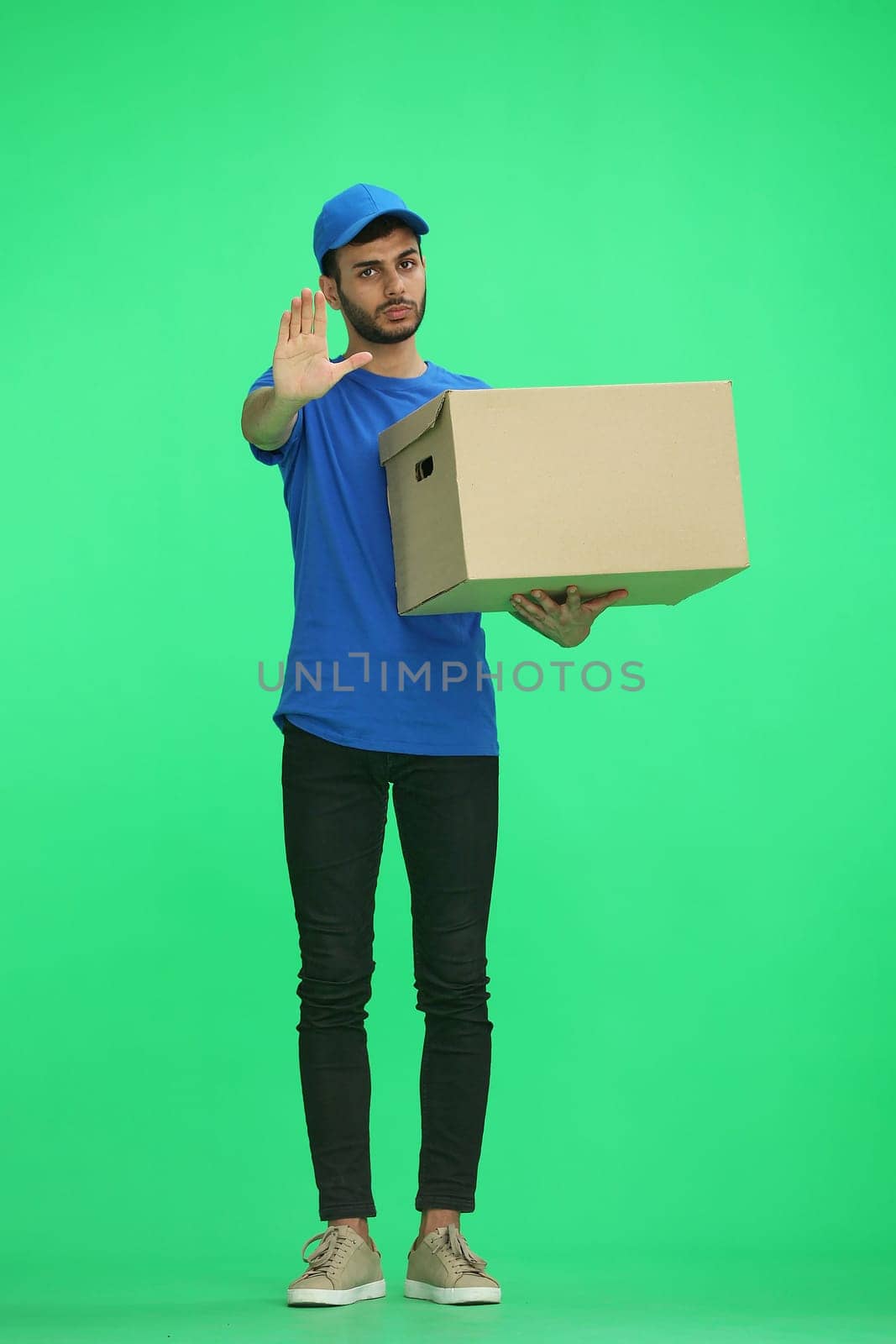 A man on a green background with box. In profile.