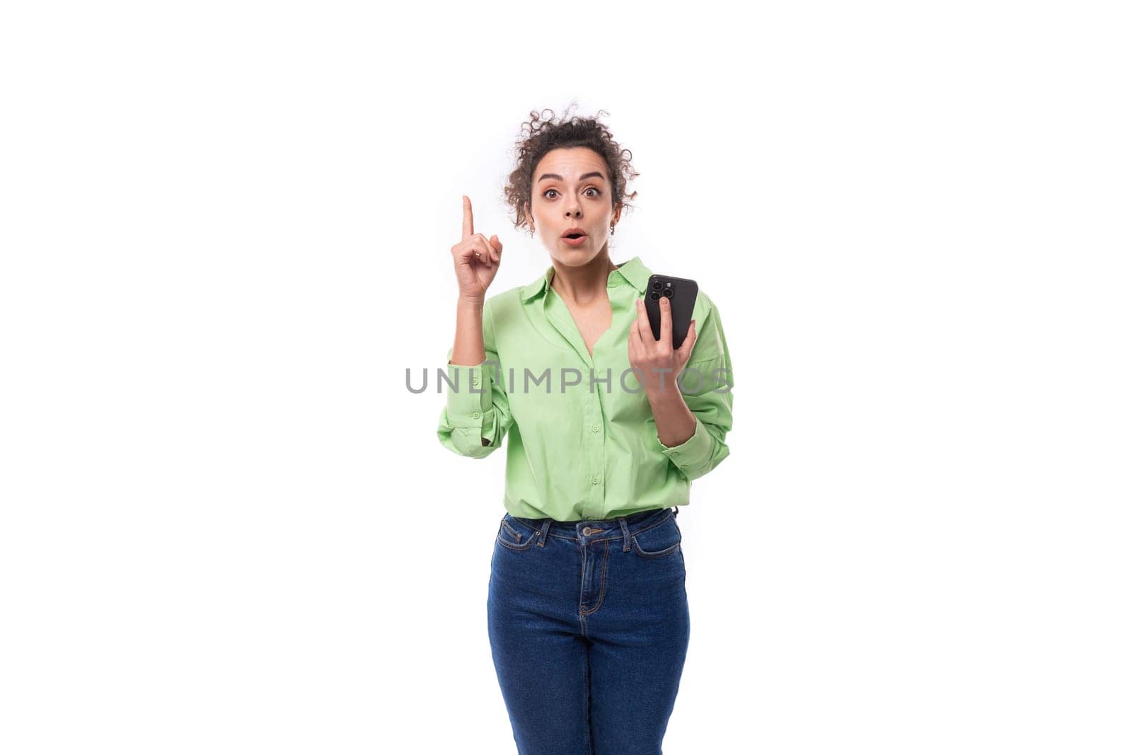 smart young slim female model dressed in light green shirt is inspired by the idea holding a smartphone in her hand by TRMK