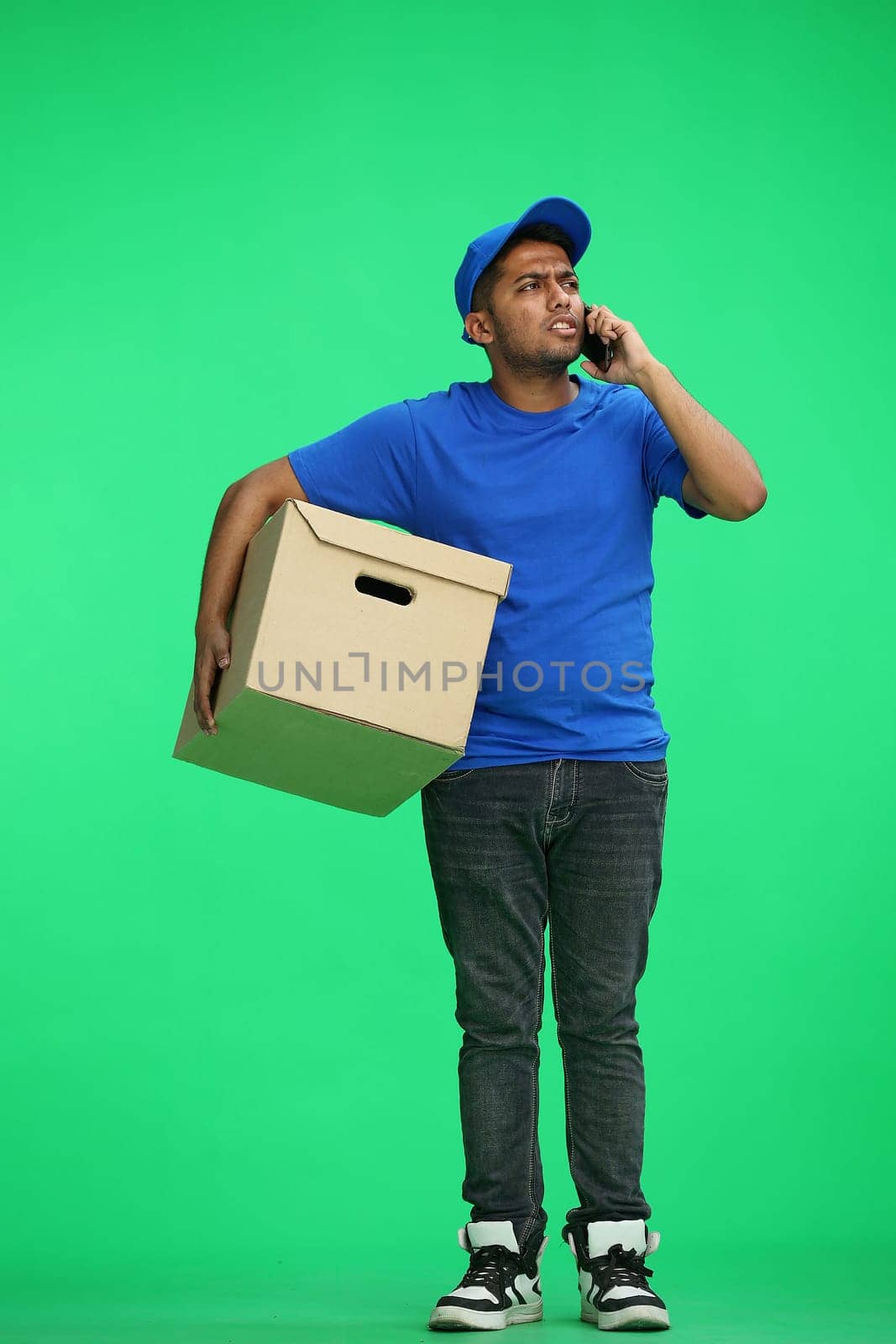 A man on a green background with box conversate on the phone.