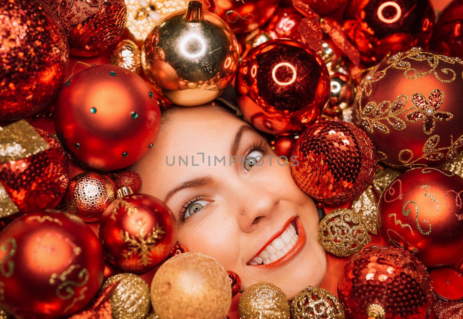 Funny woman face with wide smile in red Christmas tree toys balls. Holidays. by kristina_kokhanova