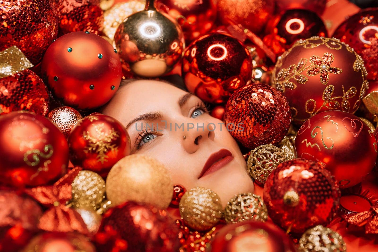 Happy woman face lights up with joy in red Christmas tree toys balls. Holidays. by kristina_kokhanova