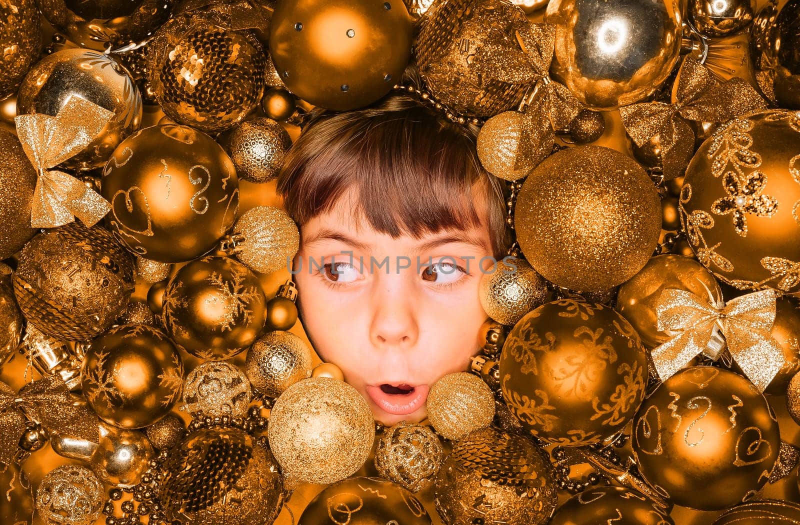 Surprised little boy face with joy in golden Christmas tree toys balls. Holiday. by kristina_kokhanova