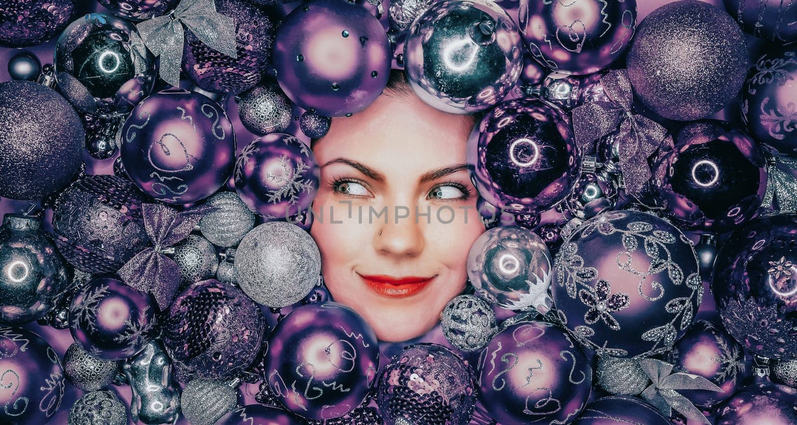 Happy woman face lights up with joy in violet Christmas tree toys balls. Holiday by kristina_kokhanova