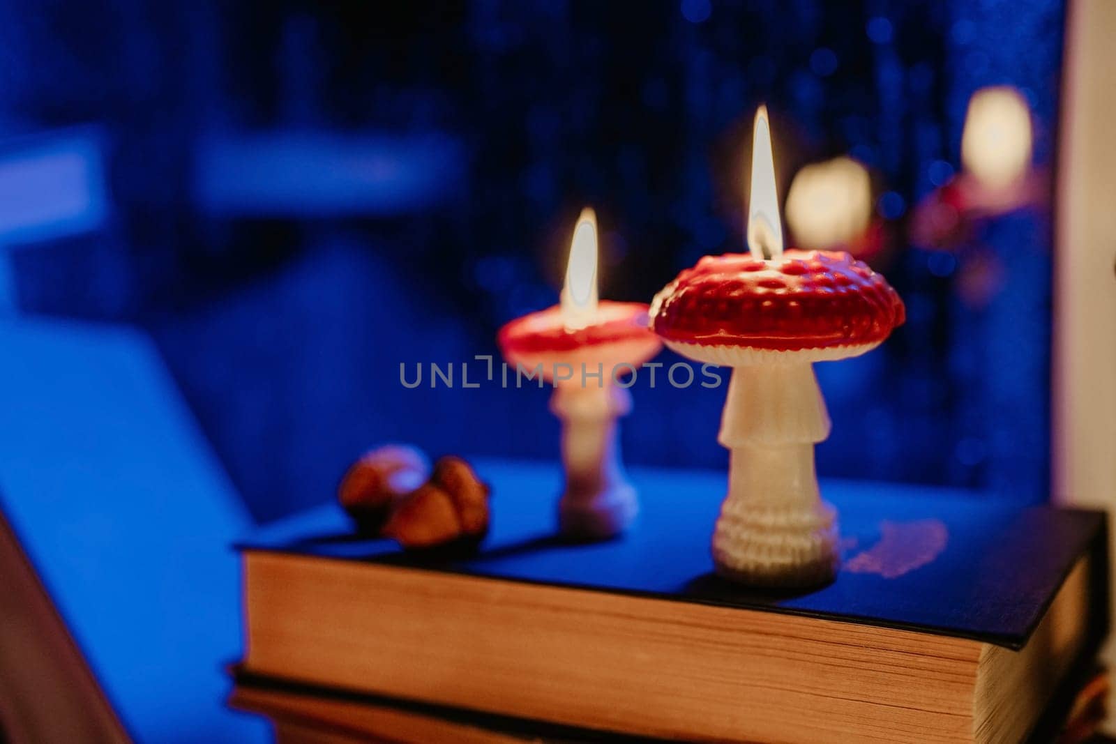 Autumn background. Mushroom candles burning on stack old books. Quiet moments. Flat lay. Cozy ambiance of fall. Seasonal promotions or tranquil visual storytelling.