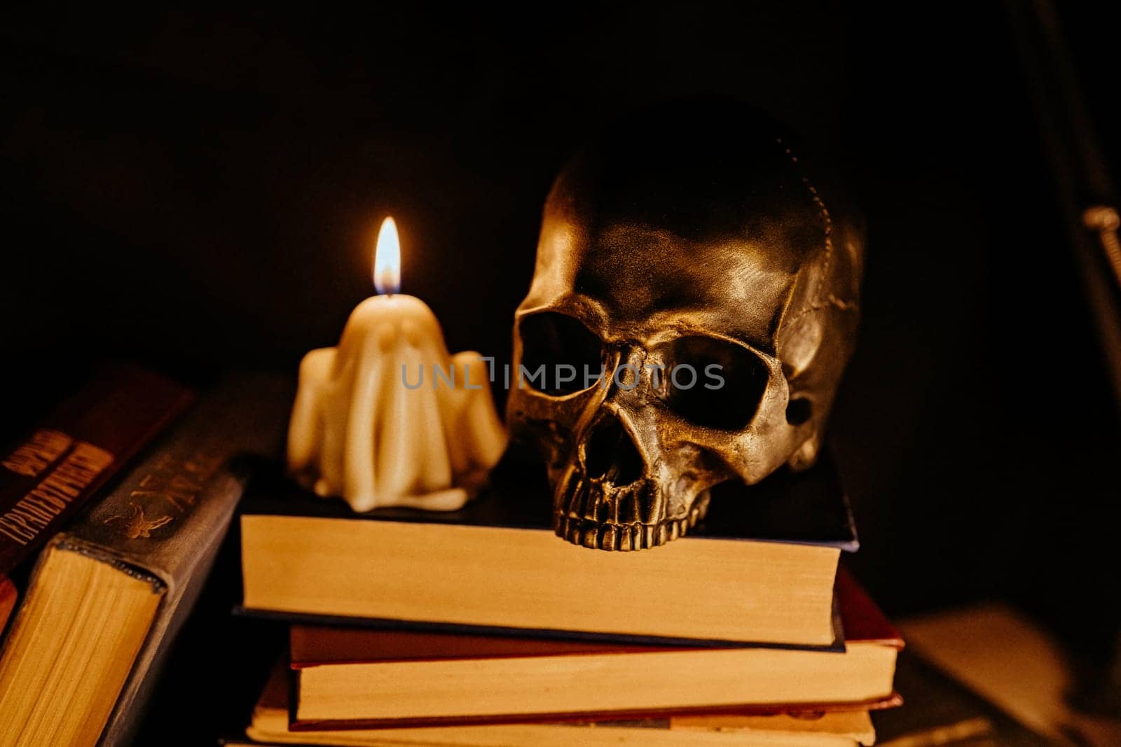 Mystique background - bronze human skull with candle. Visual gothic aesthetic. Autumn pumpkin candle, falling leaves. Ambience of fall. Seasonal promotions or dramatic visual storytelling.