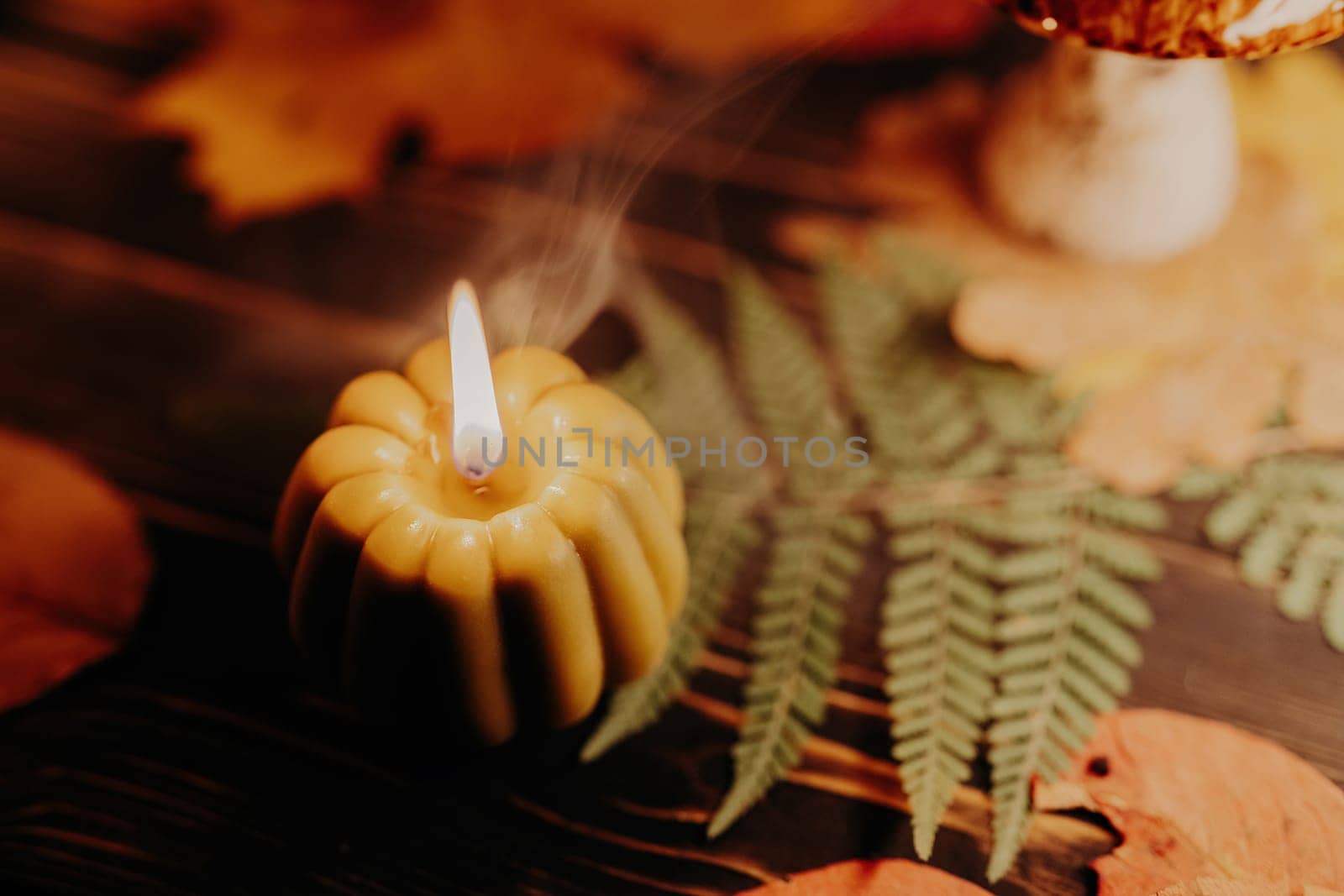 Autumn background. Pumpkin candle burning, fallen leaves. Quiet moments, hygge by kristina_kokhanova