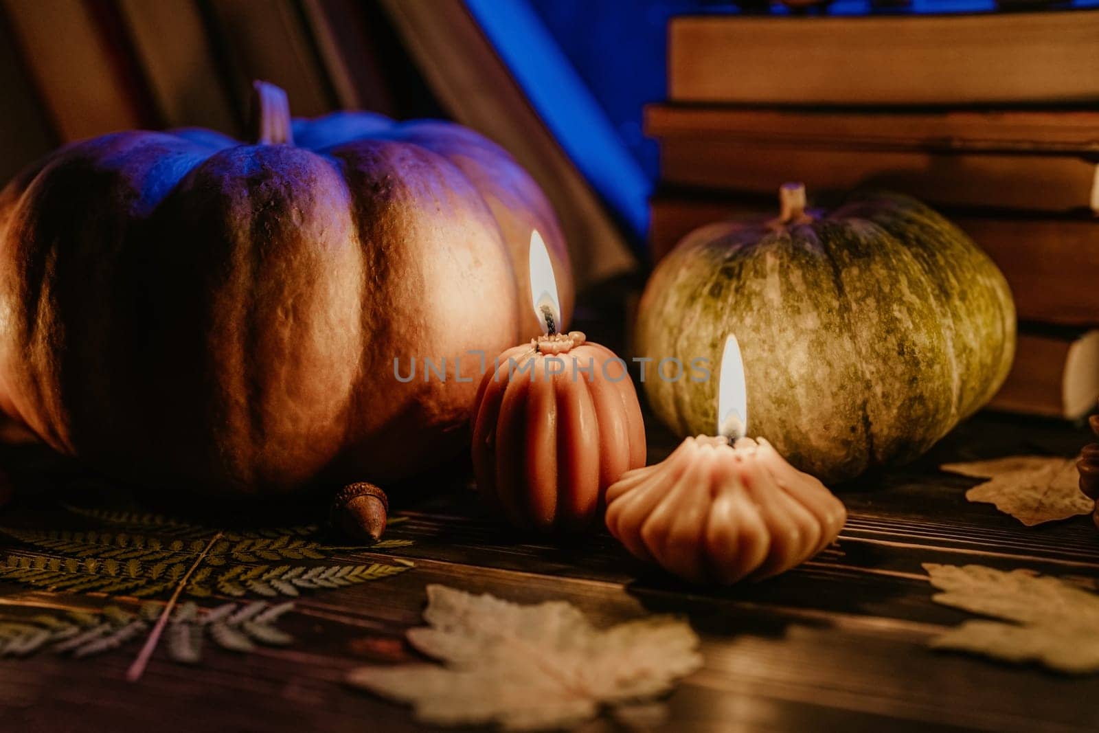 Autumn background. Pumpkin candle, orange fallen leaves. Flat lay. Cozy ambiance of fall, candle burning. Seasonal promotions or tranquil visual storytelling.