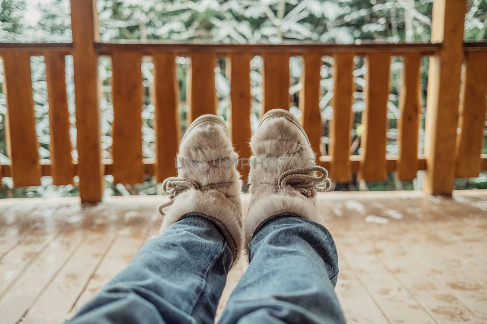 Woman legs in winter shoes - fur trendy boots on wooden balcony background. High quality photo