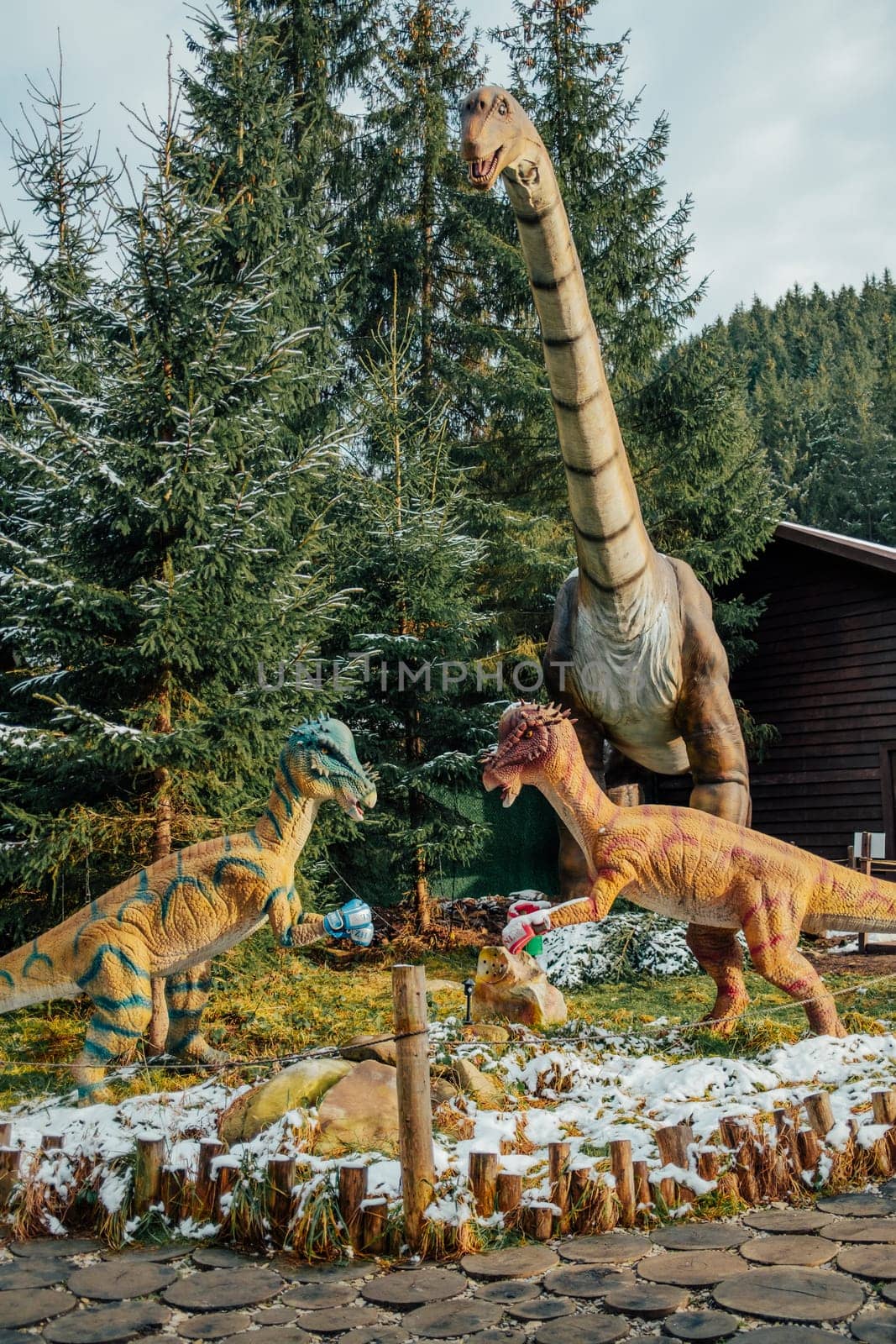 Bukovel, Ukraine - December 2023. Attraction statue of dinosaurs model in Dinopark, winter forest park in nature. Modern exhibition for children and adults. Education concept. High quality photo