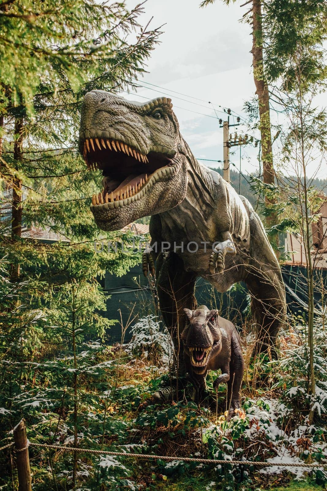 Bukovel, Ukraine - December 2023. Attraction statue of dinosaurs model in Dinopark, winter forest park in nature. Modern exhibition for children and adults. Education concept. High quality photo