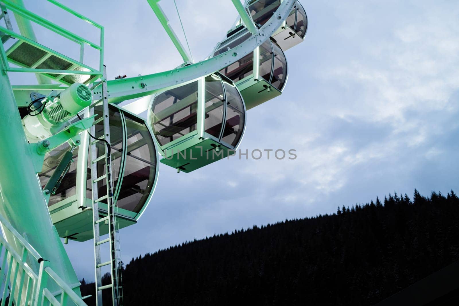Modern colorful ferris wheel free cabins over evening sky at amusement park. High quality photo