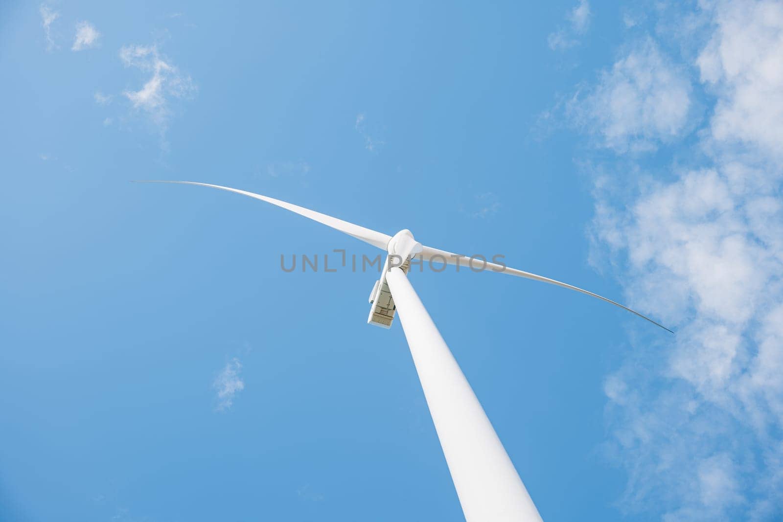 Atop a mountain windmill farm turbines illustrate efficient clean energy generation. Modern technology fosters sustainable development under the clear vast blue sky.