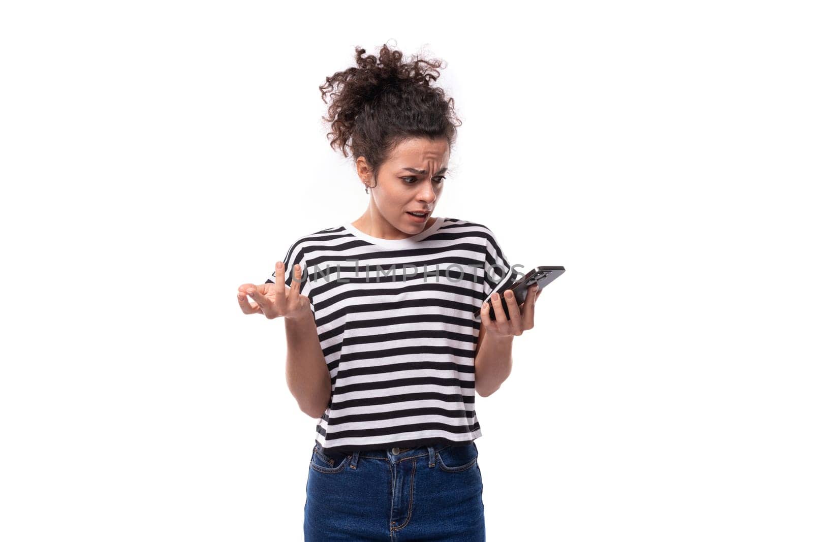 young well-groomed curly woman in a summer t-shirt studies information on the phone.