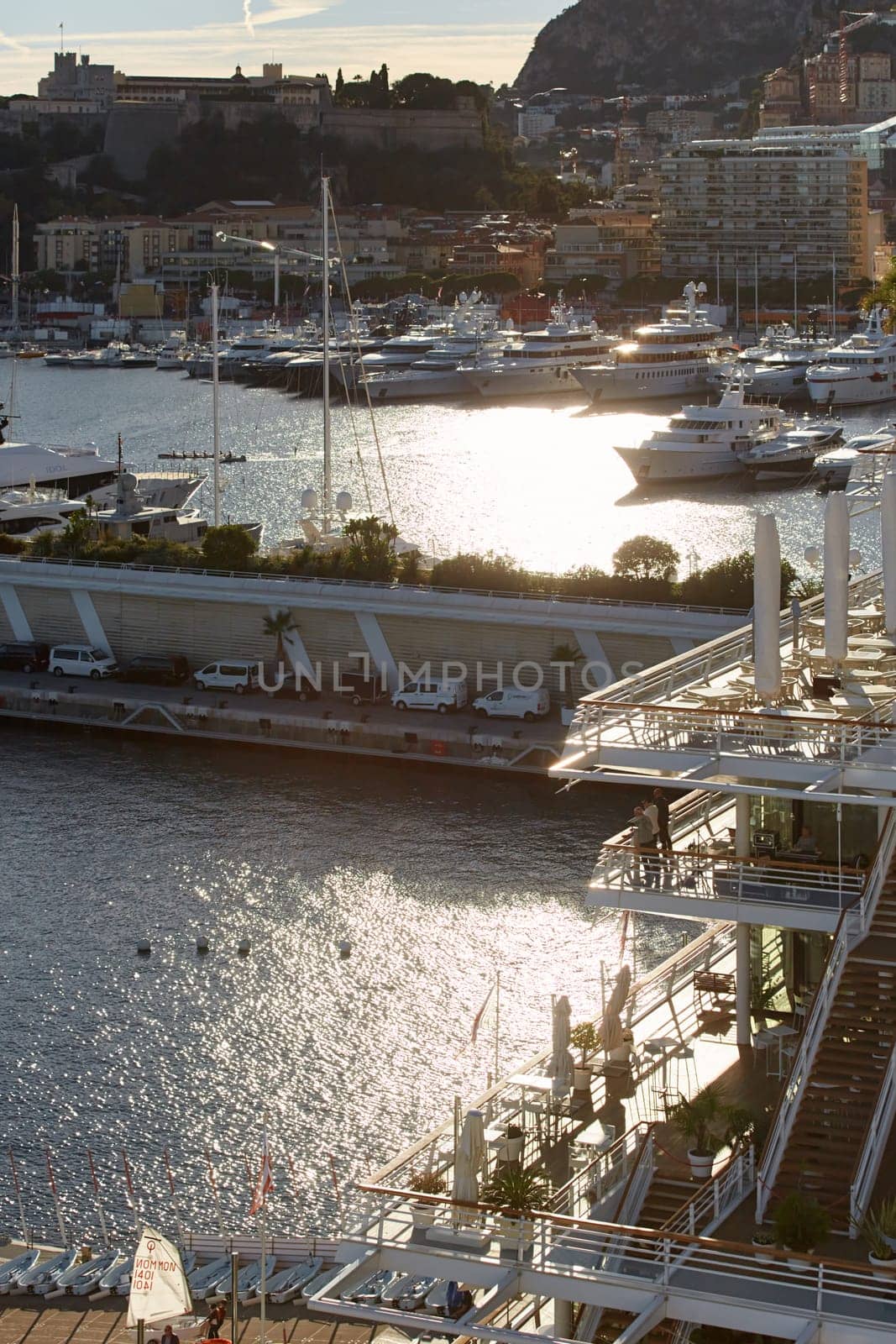 Monaco, Monte Carlo, 18 October 2022: Sunset panorama of port Hercule, moored mega yacht, sun reflection. High quality photo