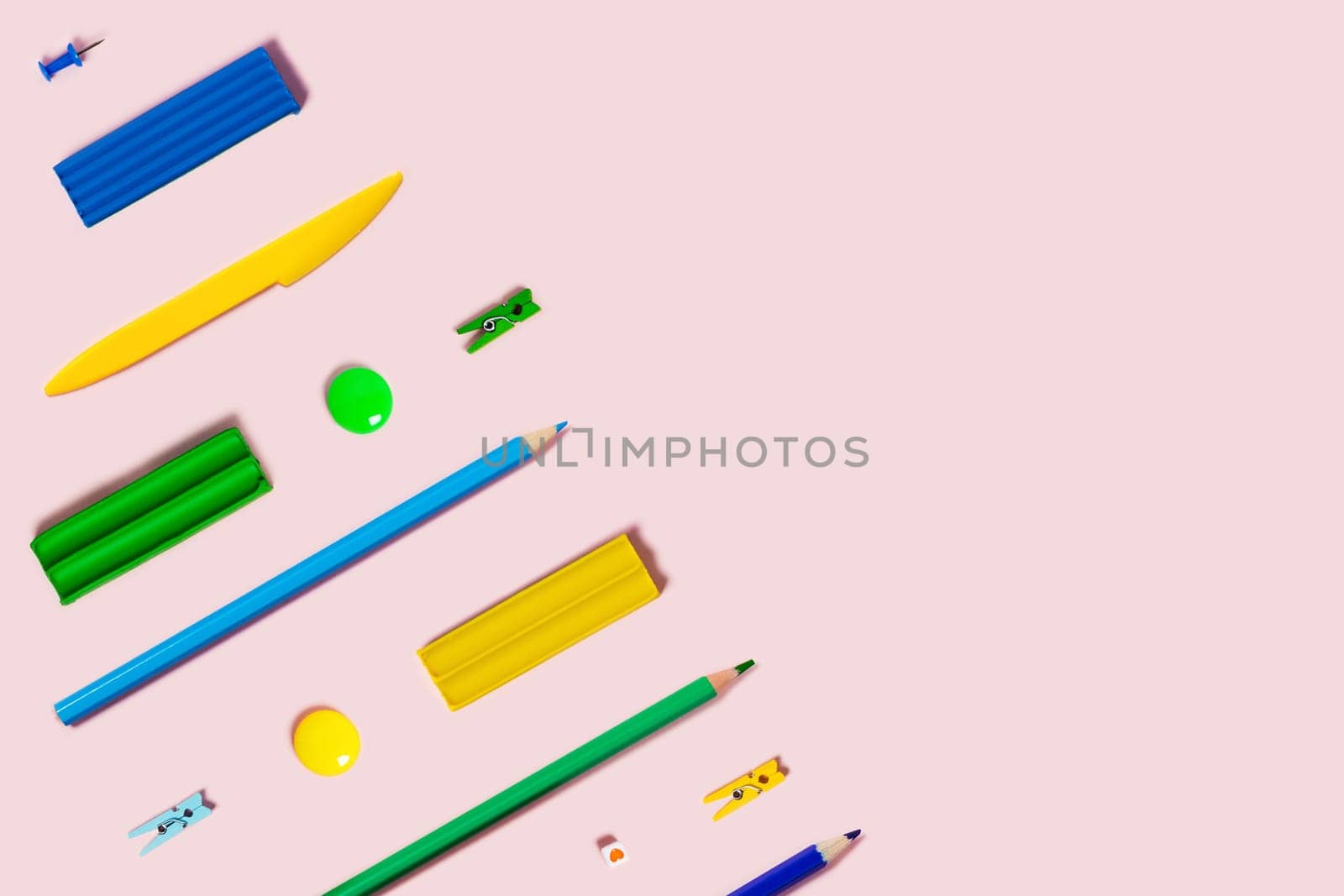 Back to school flat lay with colored pencils, plasticine, and paper clips.