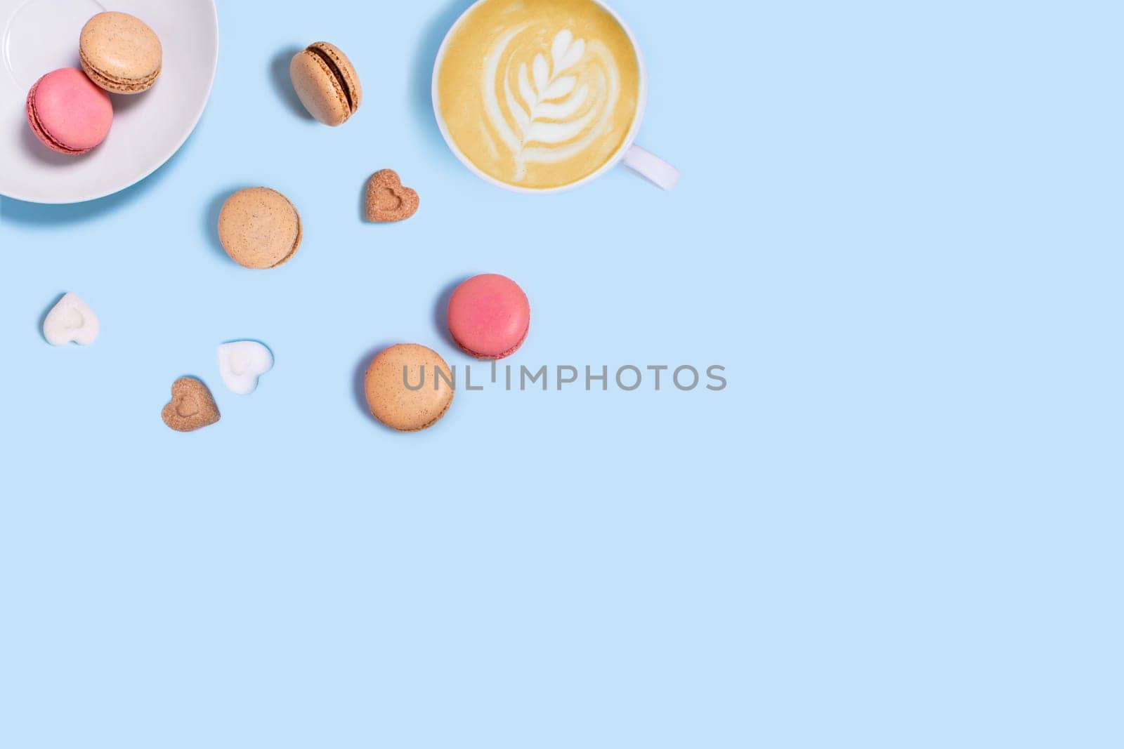 Blue background with macaroons, sugar and cup of coffee. Top view with space for your text.