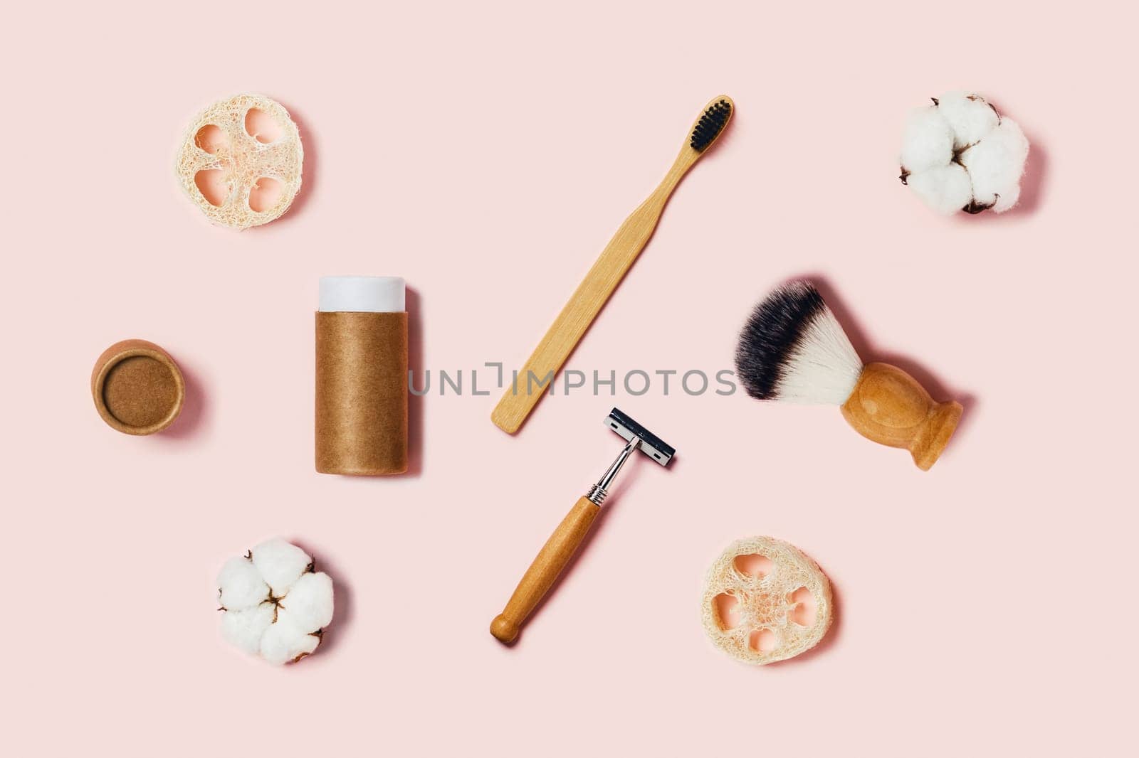 Bathroom accessories on pink background. Natural bamboo toothbrush, sponges, cotton flowers, shaving brush. Flat lay, top view.