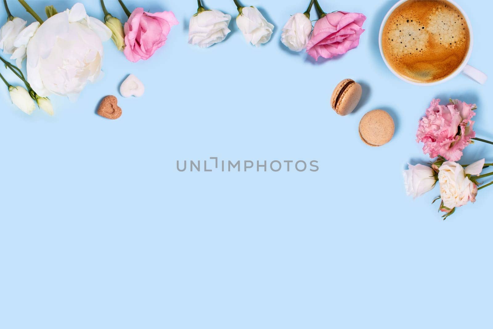 Blue background with cup of tasty coffee, macaroons, peonies and roses. Top view with space for your text.