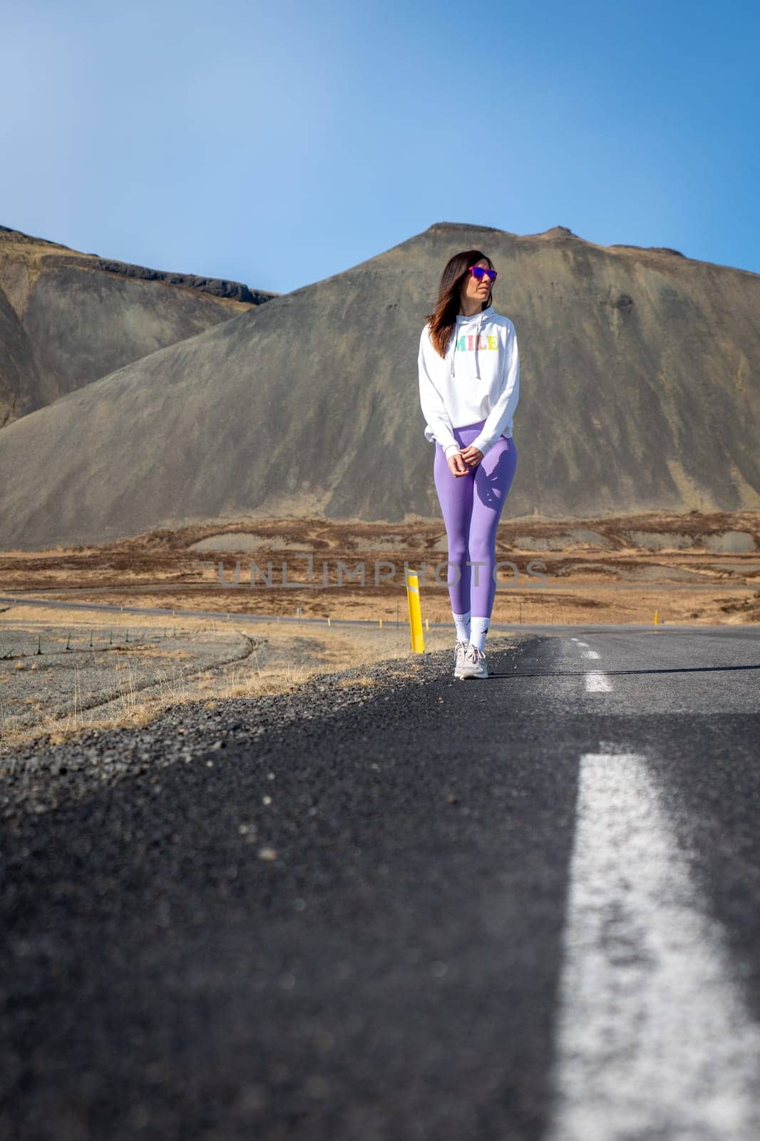 Woman wearing purple leggings on a road in Iceland by LopezPastor