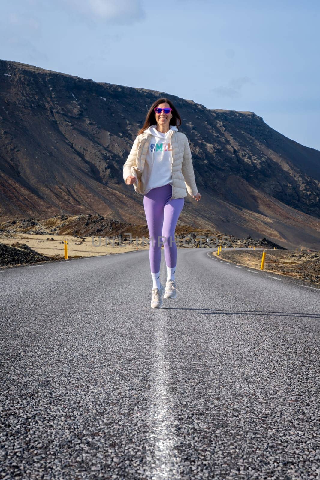 Woman running in wearing purple leggings on a road in Iceland