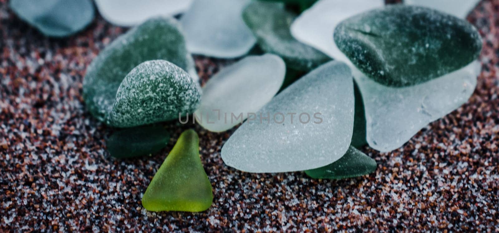 Sand mediterranean beach and stones photo. Glass stones from broken bottles polished by the sea. Front view photography with blurred background. High quality picture for wallpaper, travel blog