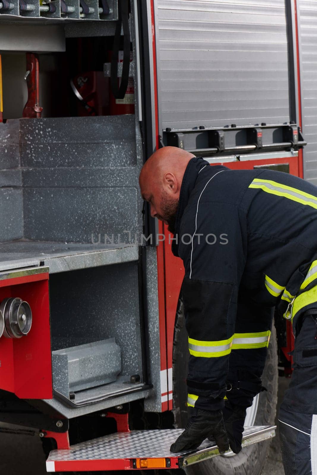 A firefighter meticulously prepares a modern firetruck for a mission to evacuate and respond to dangerous situations, showcasing the utmost dedication to safety and readiness in the face of a fire emergency by dotshock