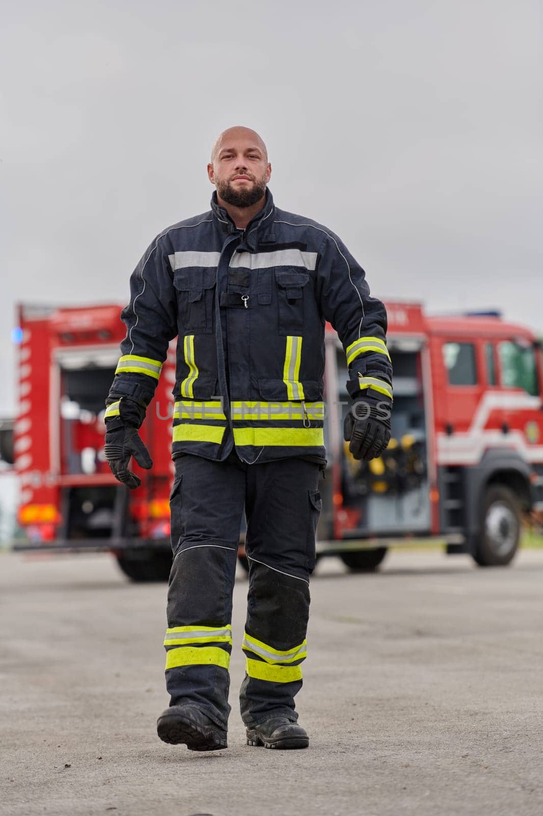 A symbolically brave firefighter strides forward with unwavering courage, epitomizing dedication and leadership, while behind him, a modern firetruck stands ready for firefighting actions, capturing the essence of heroism and preparedness in the face of emergency by dotshock