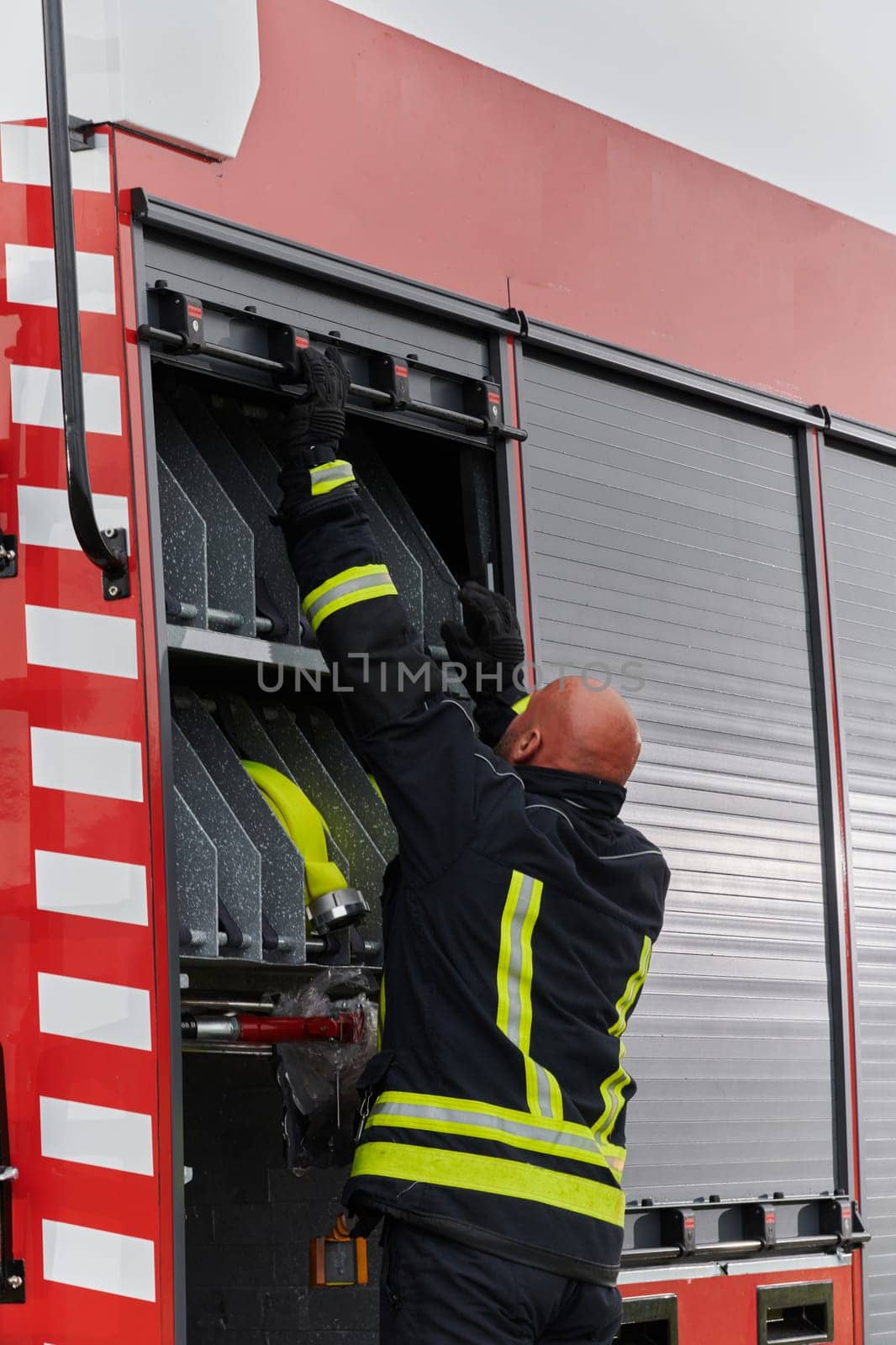 A firefighter meticulously prepares a modern firetruck for a mission to evacuate and respond to dangerous situations, showcasing the utmost dedication to safety and readiness in the face of a fire emergency by dotshock