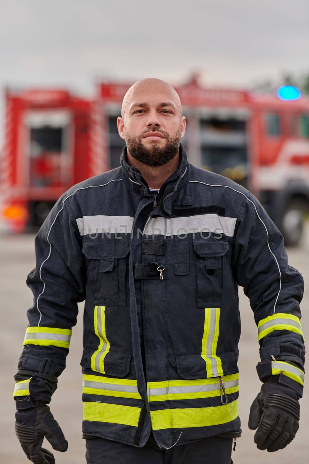 A symbolically brave firefighter strides forward with unwavering courage, epitomizing dedication and leadership, while behind him, a modern firetruck stands ready for firefighting actions, capturing the essence of heroism and preparedness in the face of emergency by dotshock