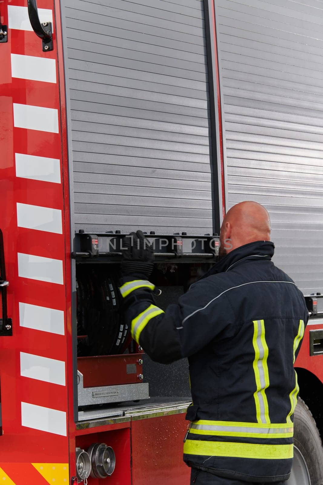 A firefighter meticulously prepares a modern firetruck for a mission to evacuate and respond to dangerous situations, showcasing the utmost dedication to safety and readiness in the face of a fire emergency.