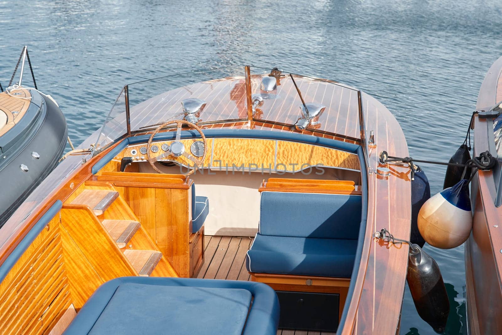 Close-up view of a relaxation area on the open teak deck of an expensive motorboat at sunny day, Monaco yacht show, large boat exhibition, wealth life, table and chairs. High quality photo